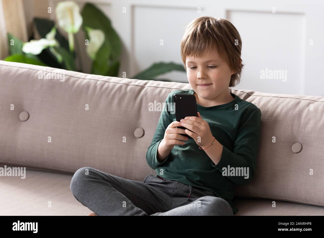 Smart little boy relax on couch using cellphone Stock Photo