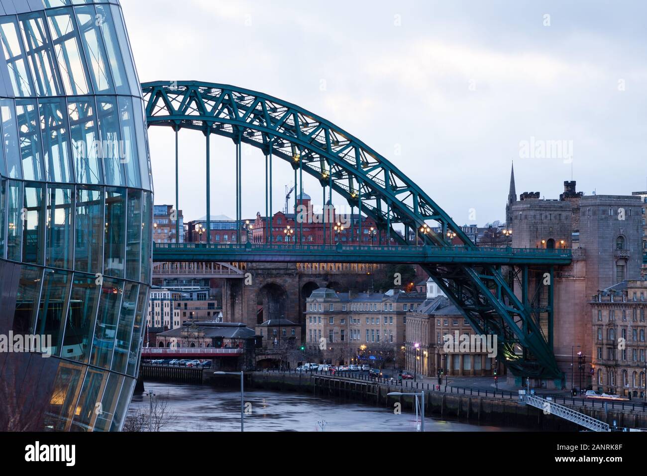 An evening view past the Sage towards the Tyne Bridge and Newcastle upon Tyne, England.  The bridge spans the River Tyne. Stock Photo