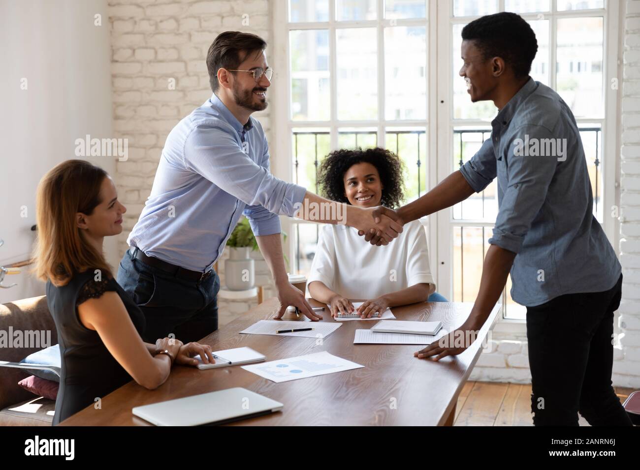 Happy diverse business partners shaking hands, making agreement Stock Photo