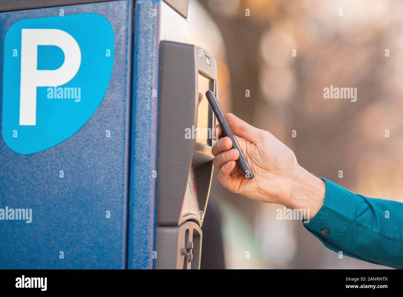 Male driver pays for parking space car contactless payment from phone Stock Photo