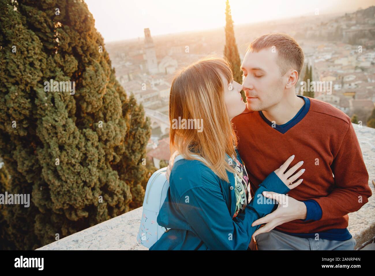 Romantic couple man and girl hug and kiss on sunset background of city Verona Italy. Travel concept Stock Photo