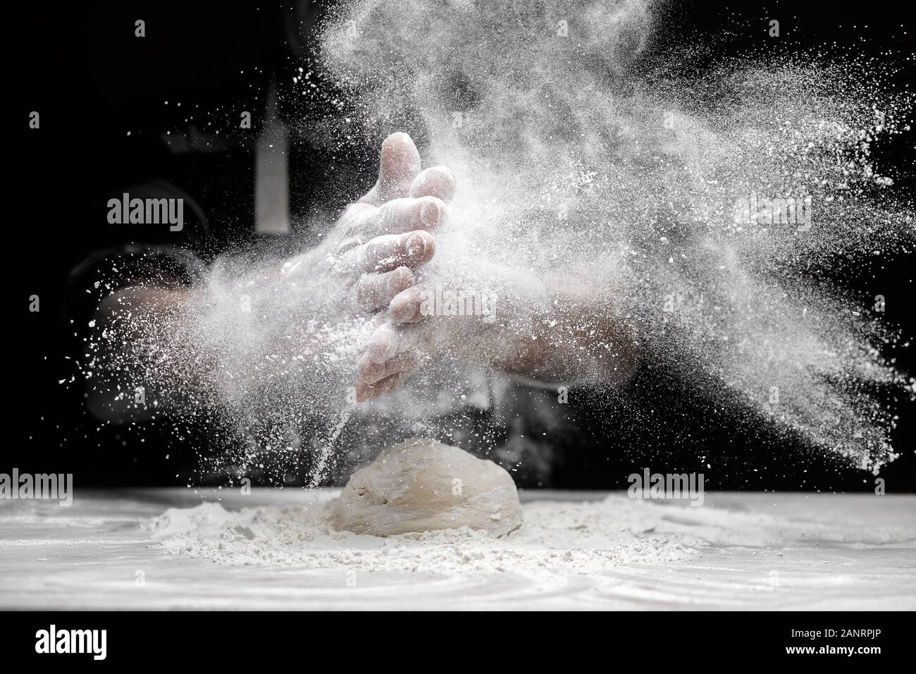 Chef man clap hand and white flour dust on black background Stock Photo