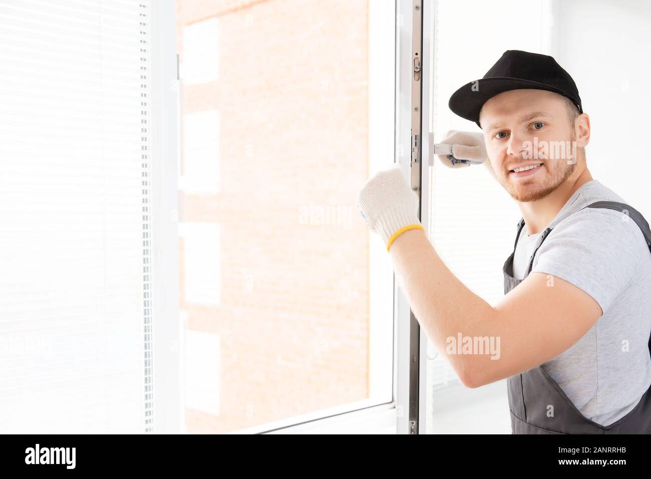 Construction worker man uses screwdriver to screw handle install plastic white upvc windows in