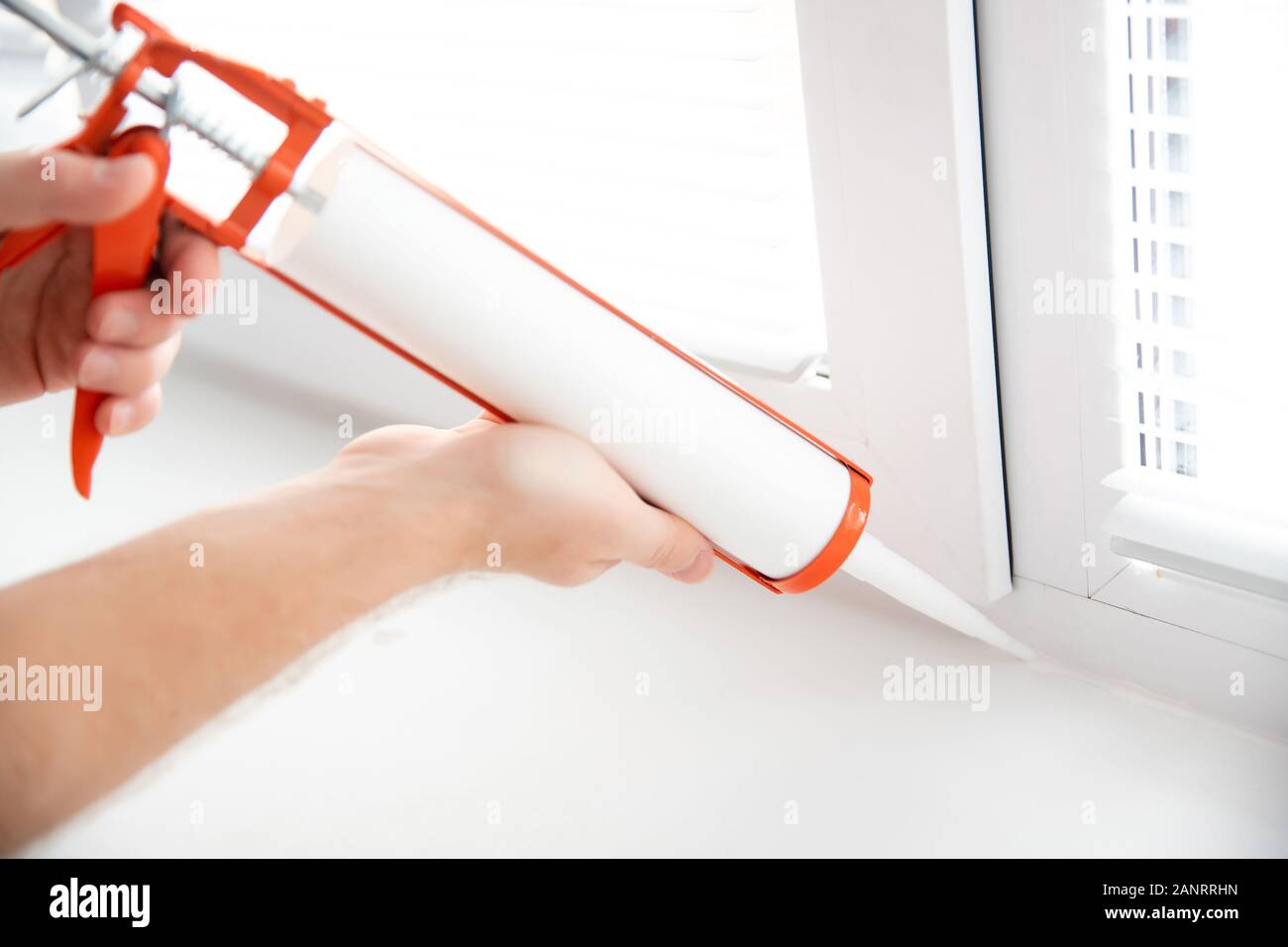 Construction worker use gun silicone tube for repairing and installing window in house Stock