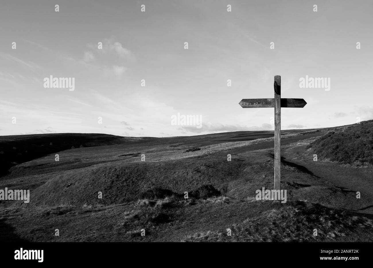 Wooden signpost at crossroads on moorland above Lastingham, North Yorkshire (landscape, black and white) Stock Photo