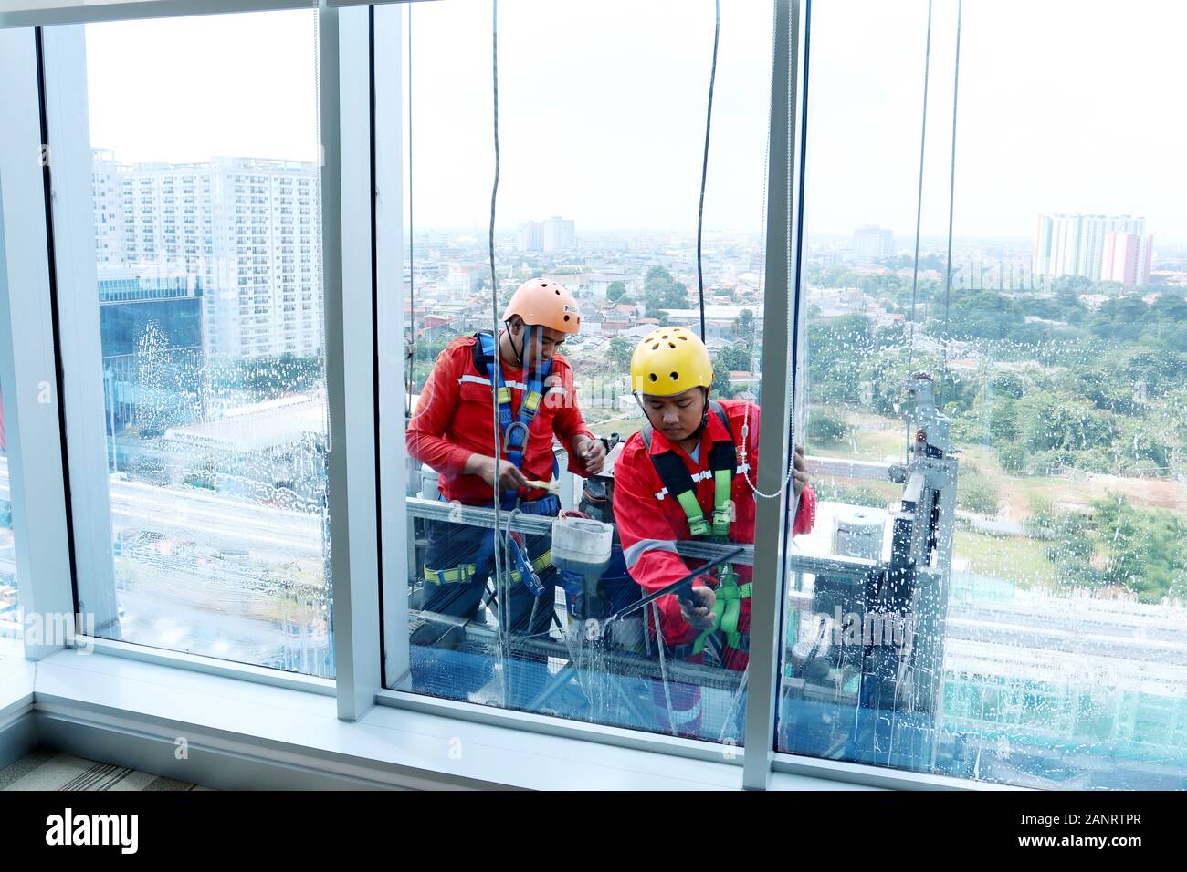 two workers cleaning windows service in high rise building in Business district Tower , Jakarta, Indonesia Stock Photo