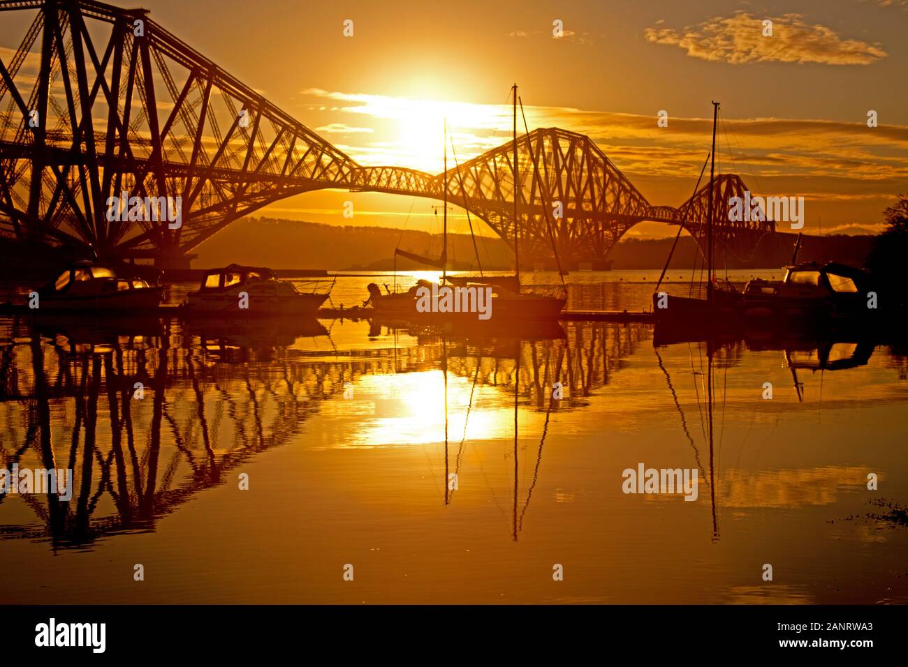 North Queensferry, Scotland, UK. 19th Jan. 2020. Just after sunrise, looking over the Forth Estuary towards Edinburgh to a silhouette of Forth Rail Bridge and small fishing boats Stock Photo
