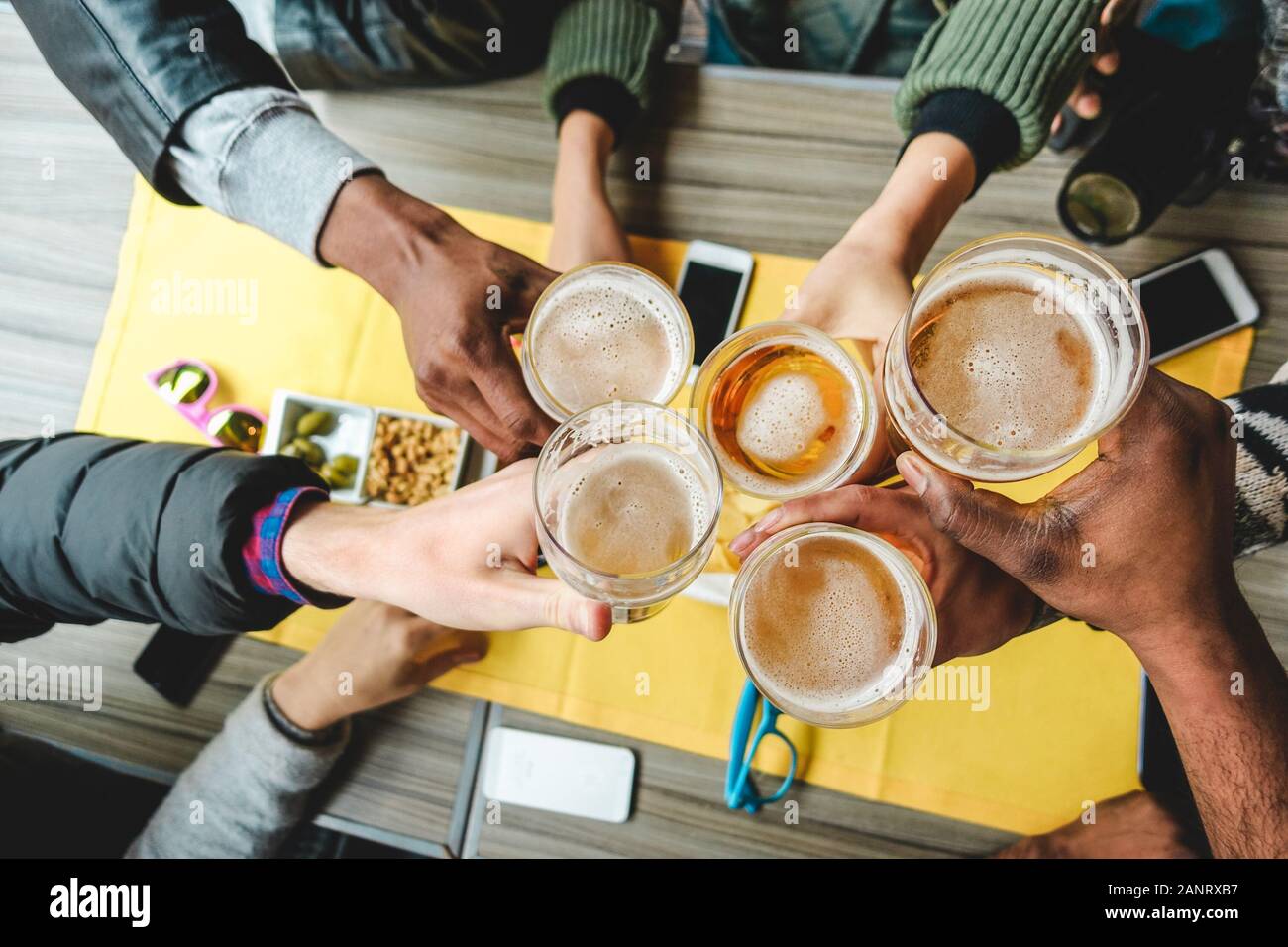 Group of friends enjoying a beer glasses in english pub restaurant - Young people cheering at vintage bar - Friendship, happy hour and party concept - Stock Photo