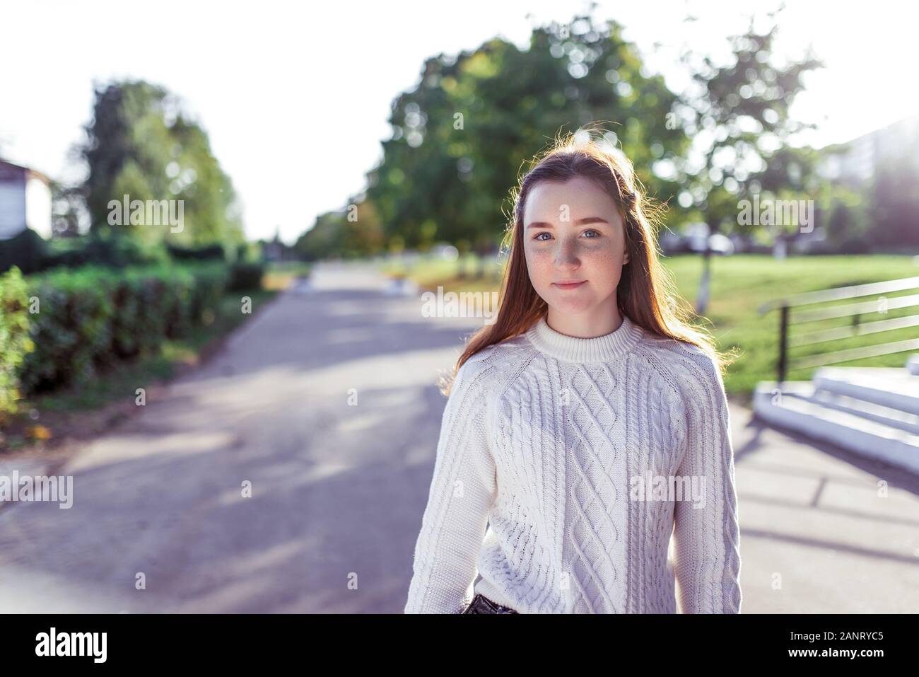 Happy smiling Girl teenager 12-15 years old, autumn day, street portrait, knitted white sweater, summer park. Resting after school. Free space for Stock Photo