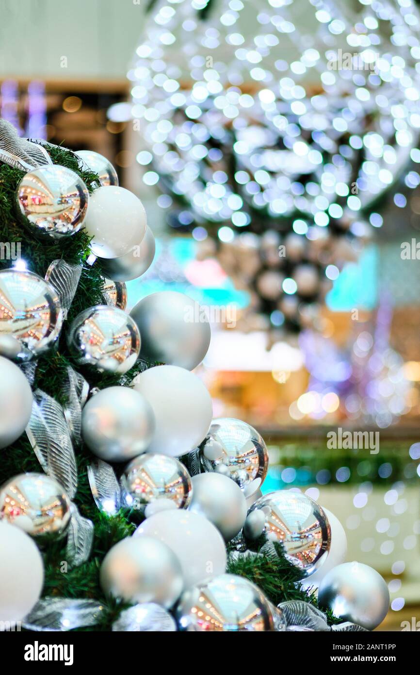 Christmas white balls on branches with a beautiful blurred background of lights. Vertical. Stock Photo