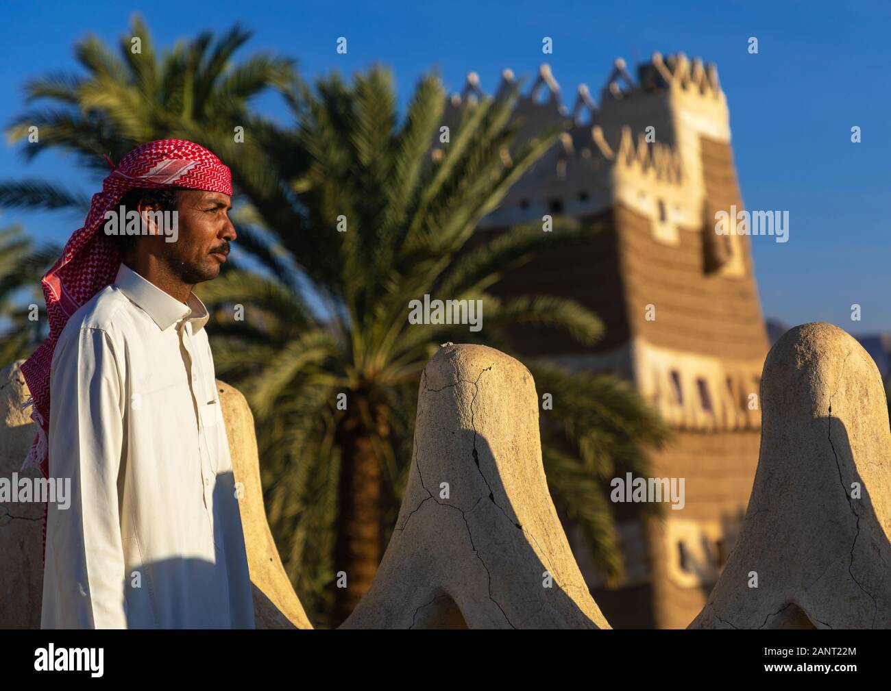 Saudi man standing on the crenelated terrace of his mud house, Najran Province, Najran, Saudi Arabia Stock Photo