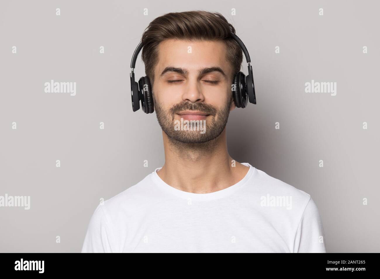 Handsome guy wearing modern wireless headphones, enjoying favorite slow music Stock Photo Alamy