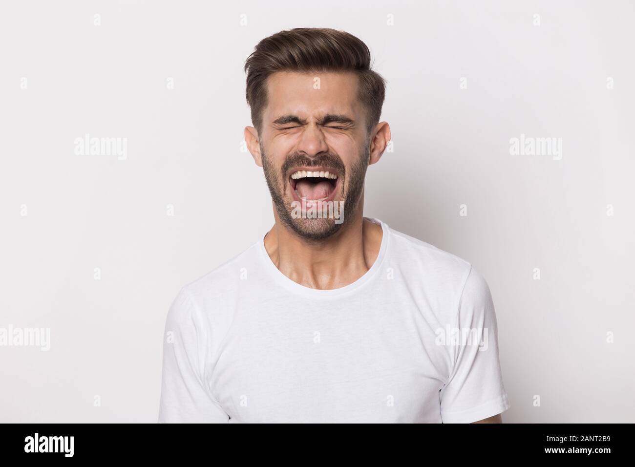 Angry stressed outraged hysterical millennial guy screaming. Stock Photo