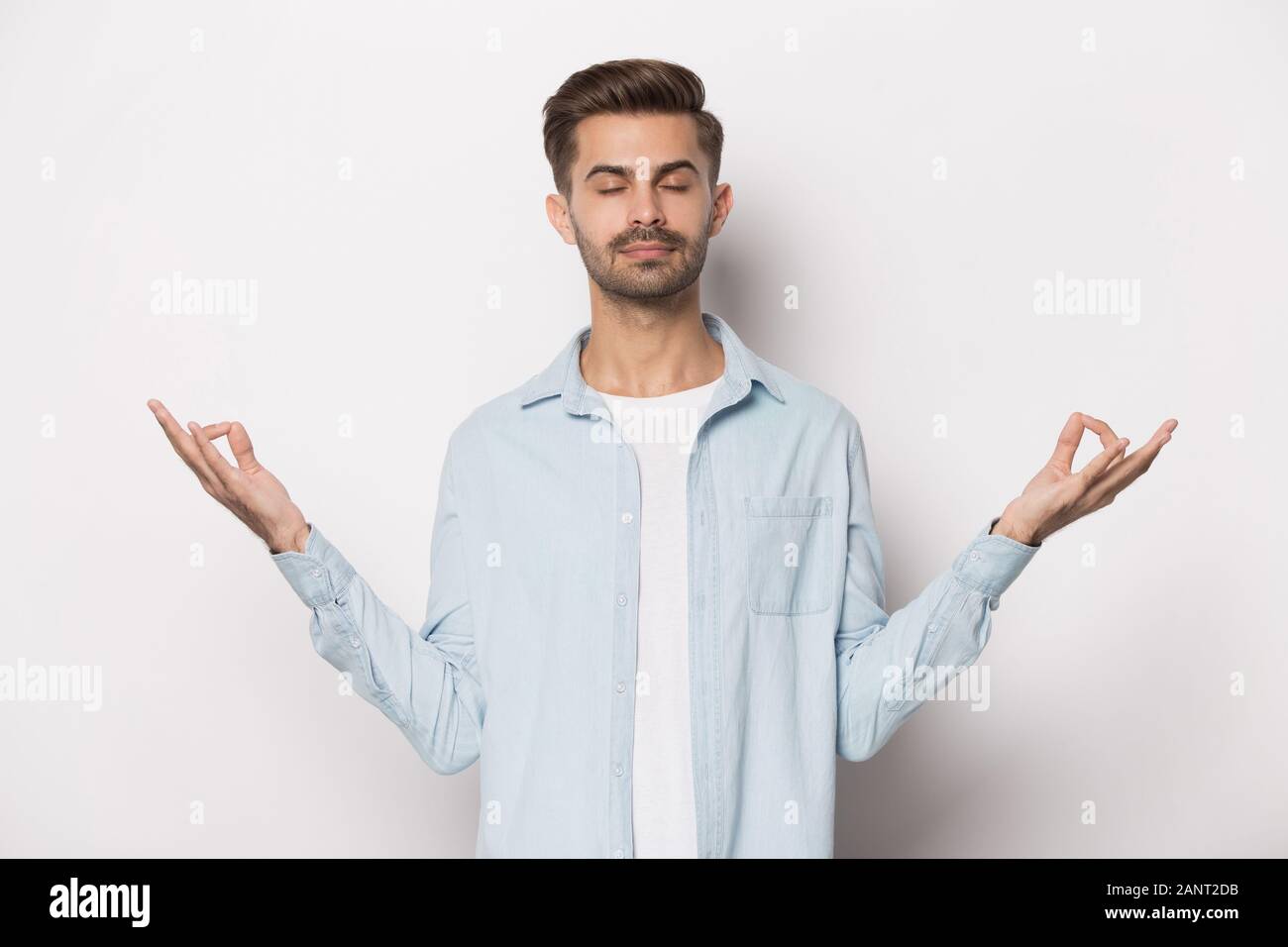 Young peaceful guy doing breathing yoga exercises. Stock Photo