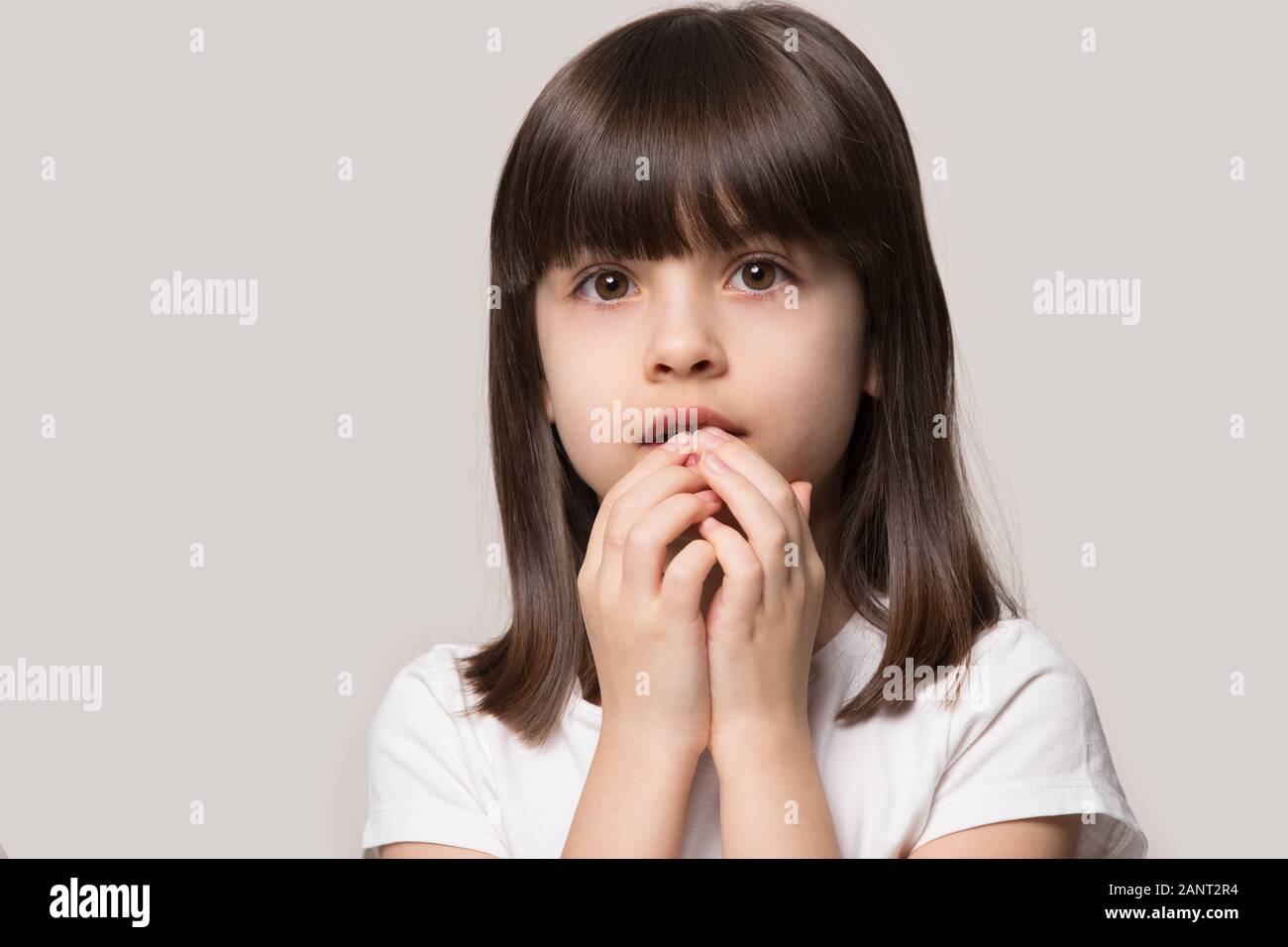 Worried about left alone little girl holding hands near mouth. Stock Photo