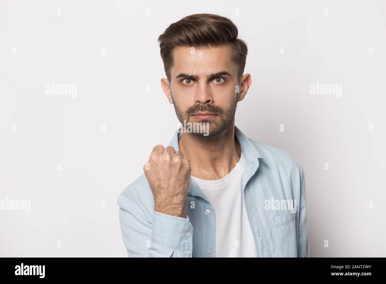 Angry young guy squeezing hand into fist, showing power. Stock Photo