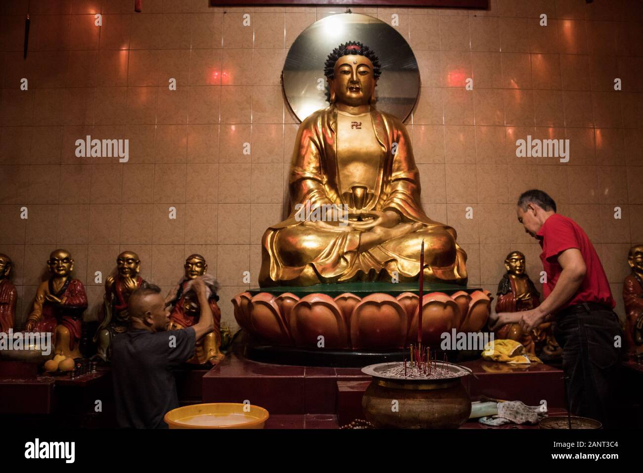 Men clean statues during the celebration at Dharma Ramsi temple in