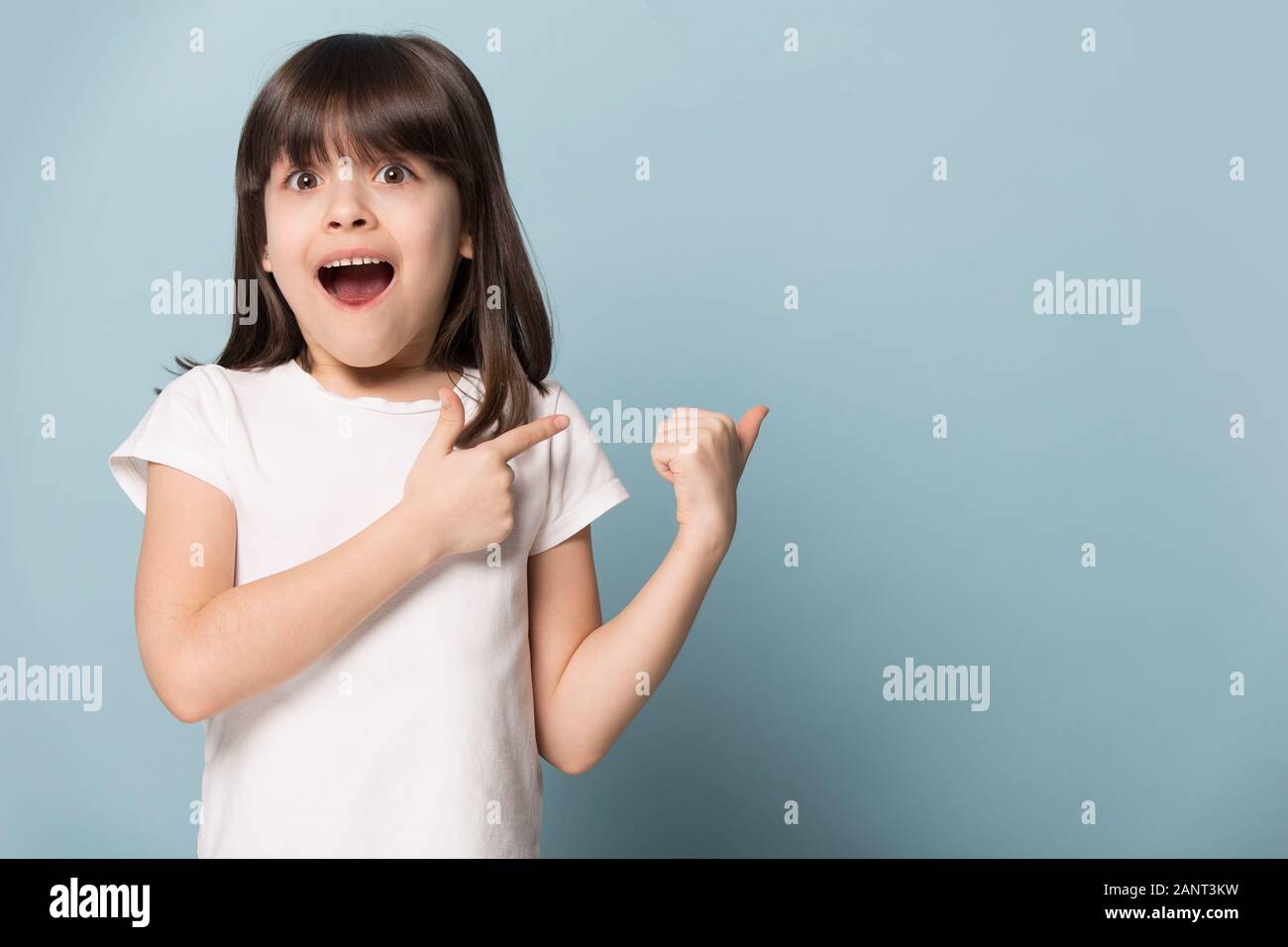 Excited gawp girl pointing back on empty copy space. Stock Photo