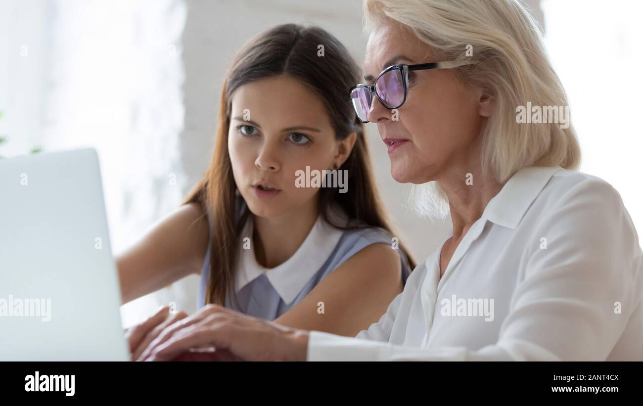 Aged apprentice young mentor working together seated at workplace desk Stock Photo