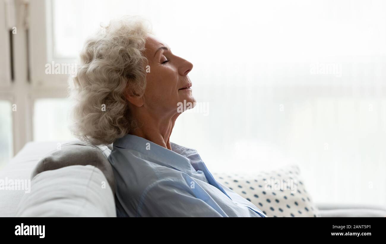 Head shot profile peaceful older woman relaxing on couch Stock Photo