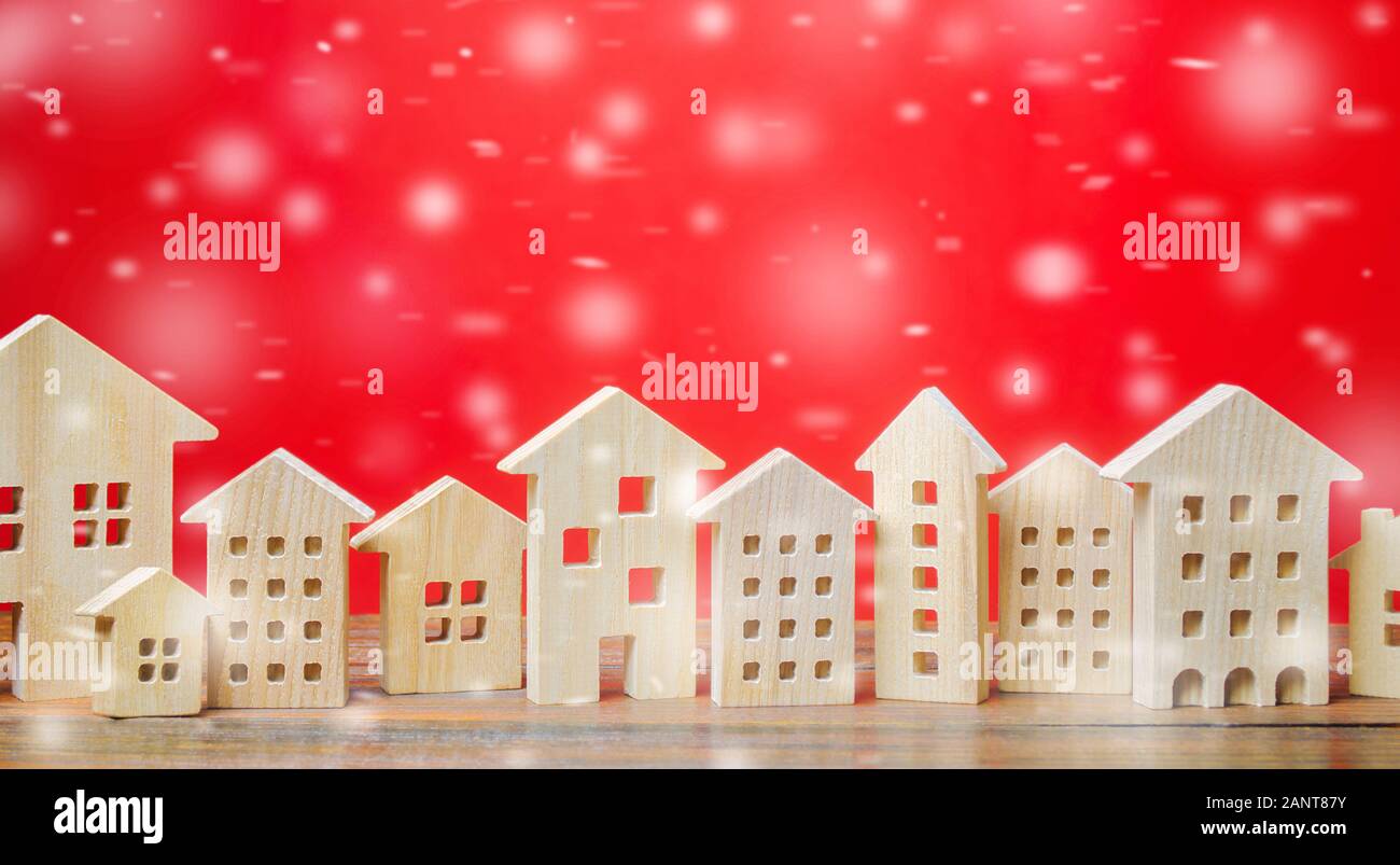 Miniature wooden houses and snowflakes on a red background. Christmas discounts and real estate sales. New Year or Xmas winter holiday. Decoration, ce Stock Photo