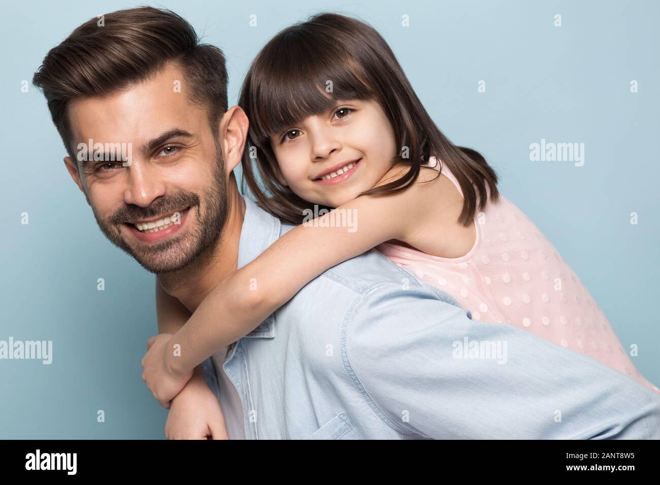 Happy young dad holding little preschool smiling daughter on back. Stock Photo