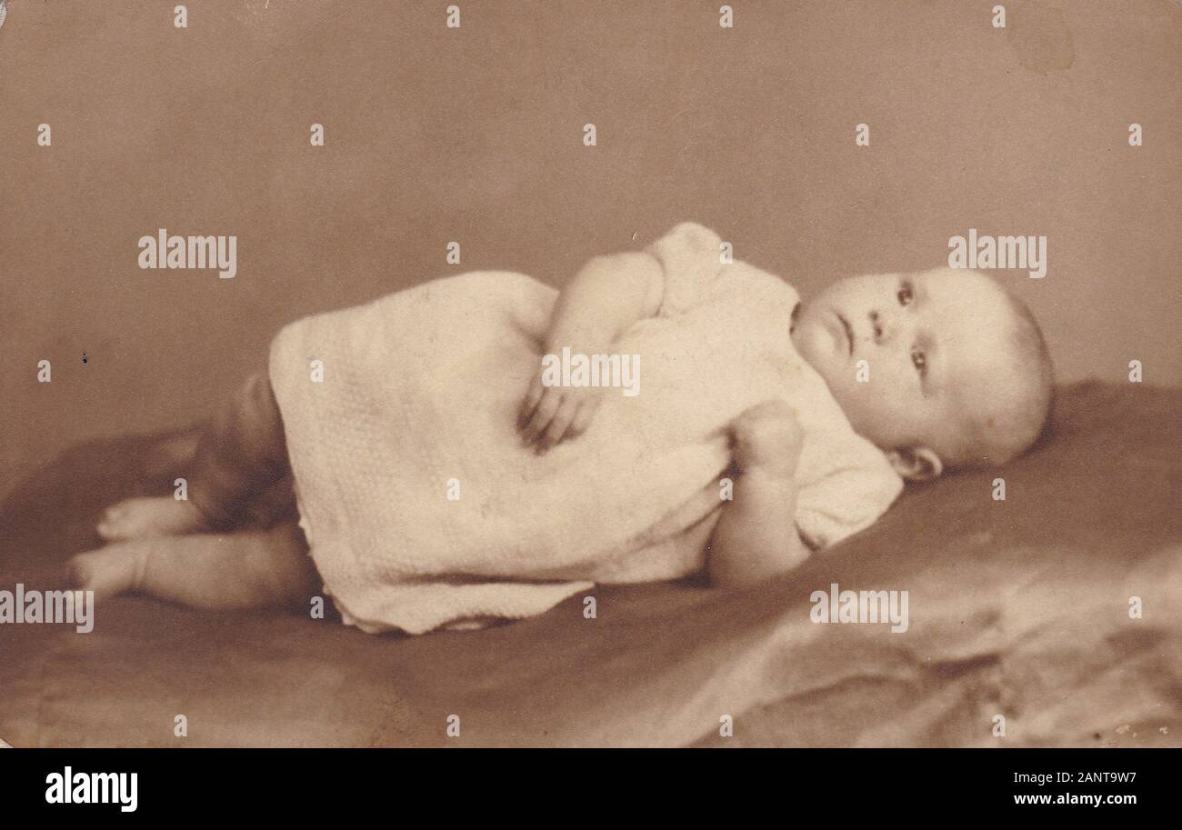 Vintage black and white 1920s photo of a young baby wearing gown. Stock Photo