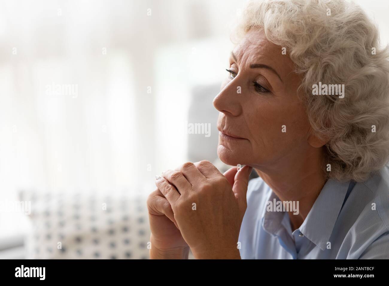 Close up thoughtful older woman worried about problem, sitting alone Stock Photo