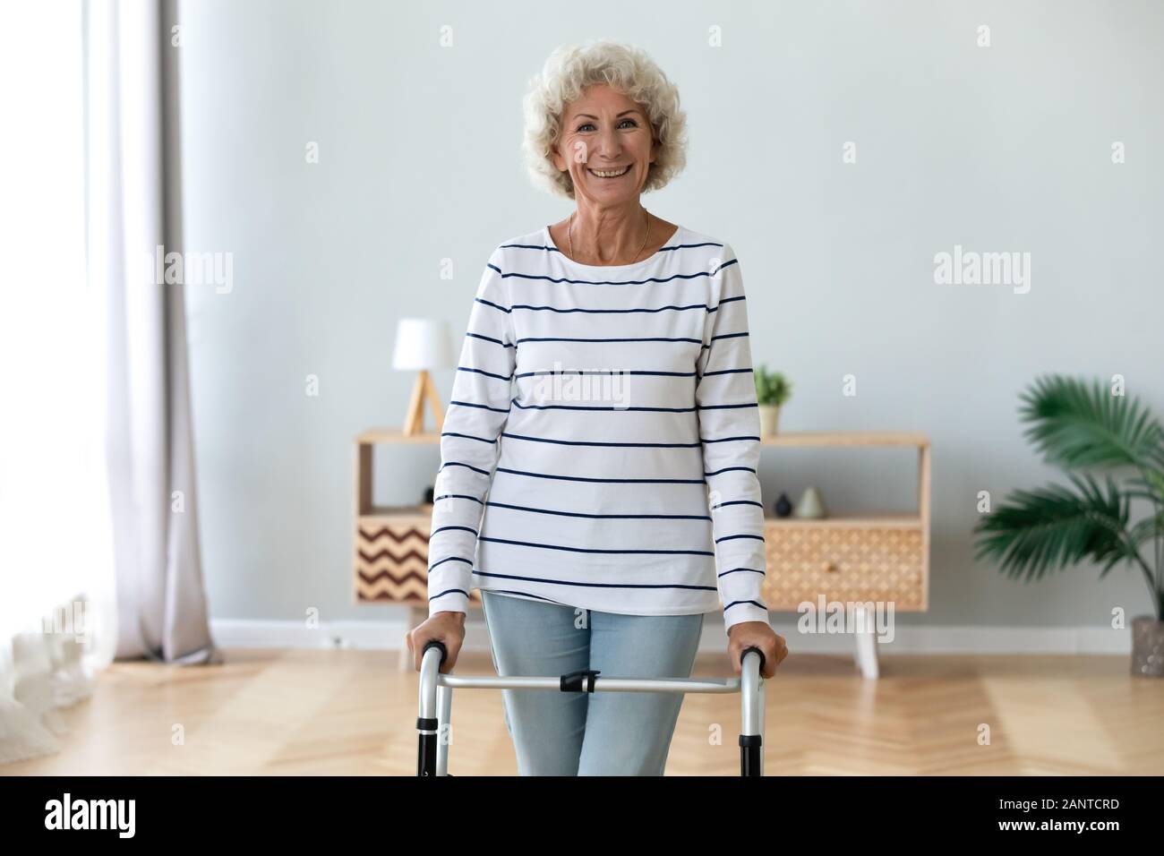 Portrait smiling disabled older woman standing with walker Stock Photo