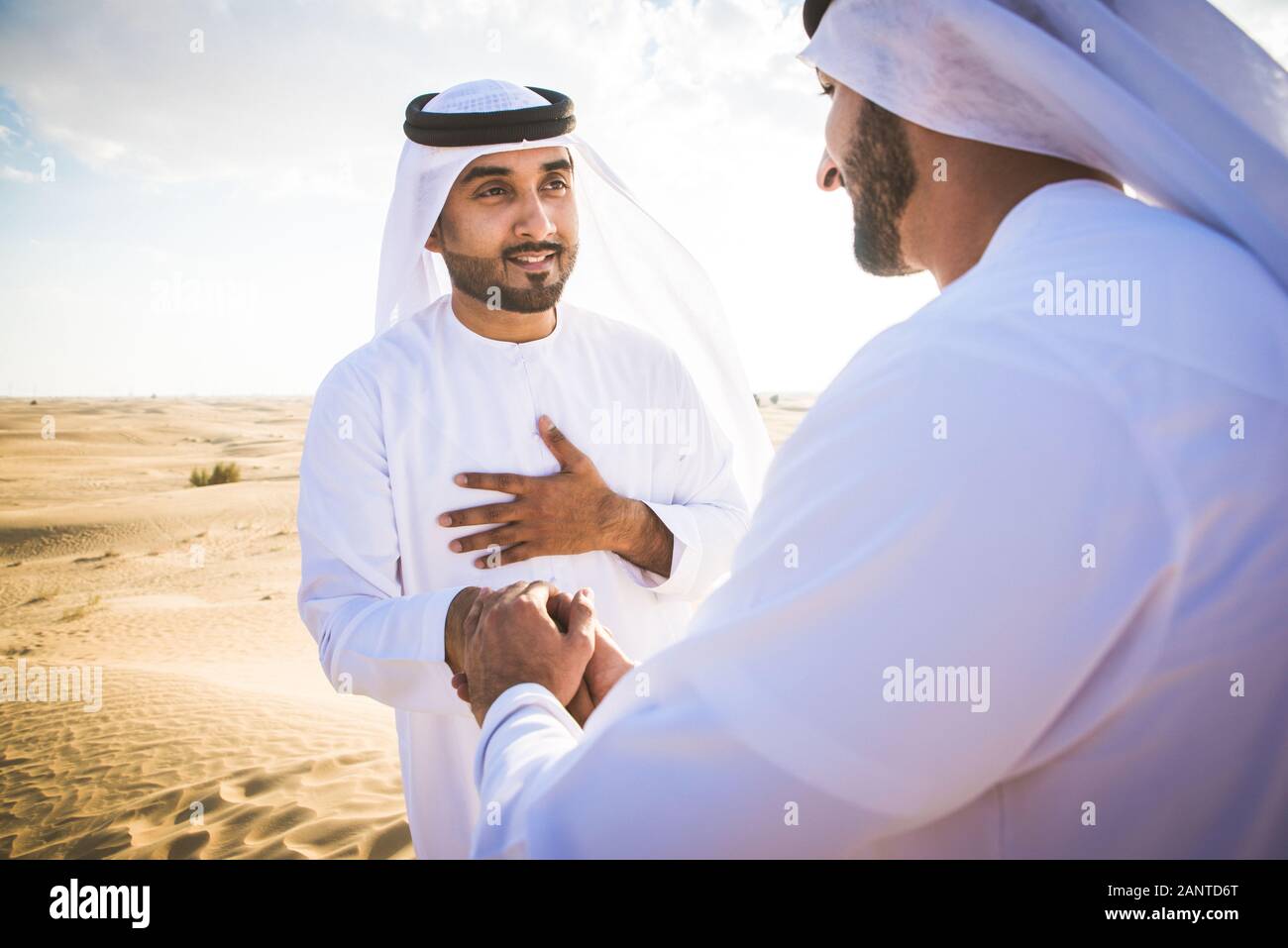 Arabian men witk kandora walking in the desert - Portrait of two middle eastern adults with traditional arabic dress Stock Photo