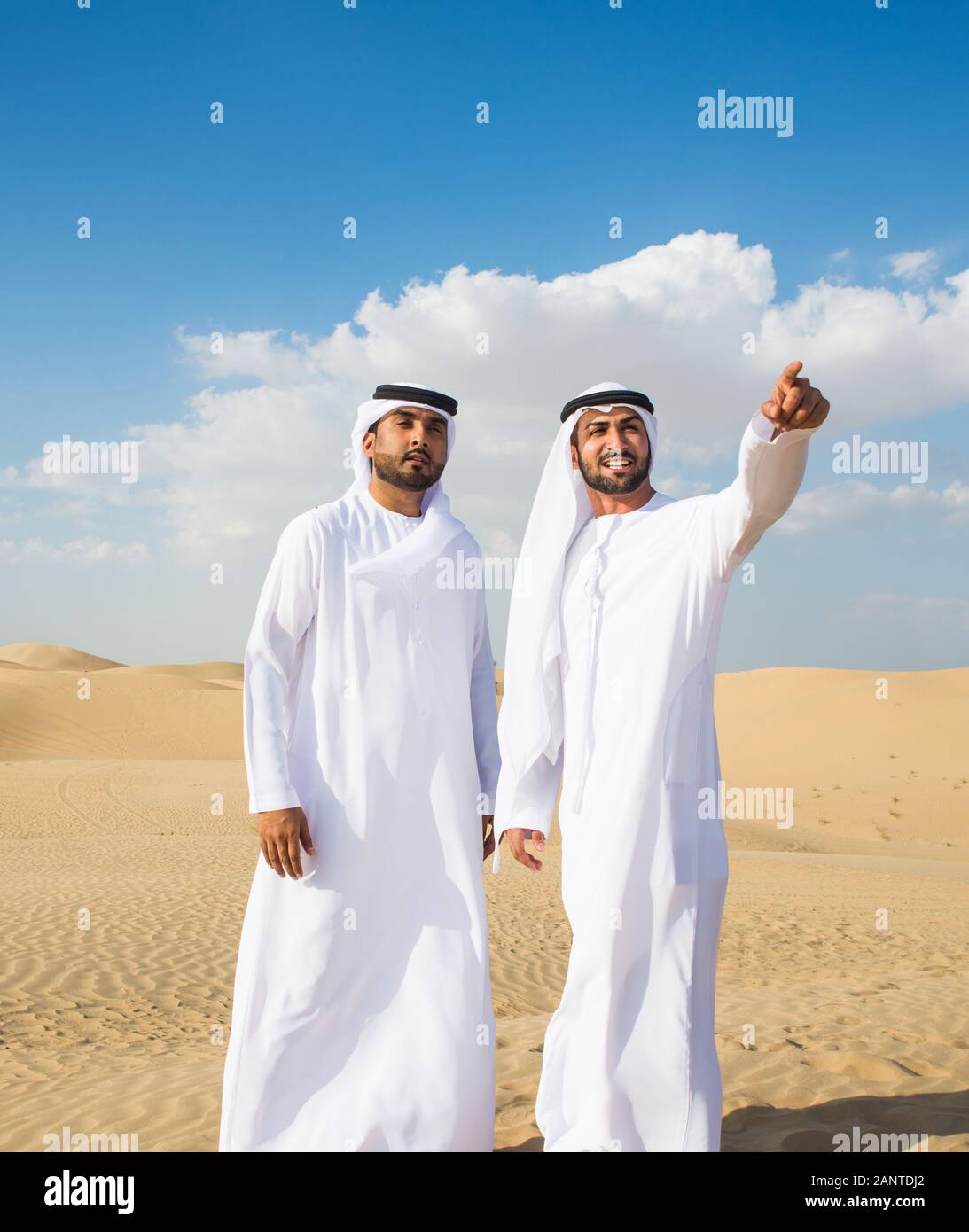 Arabian men witk kandora walking in the desert - Portrait of two middle  eastern adults with traditional arabic dress Stock Photo - Alamy