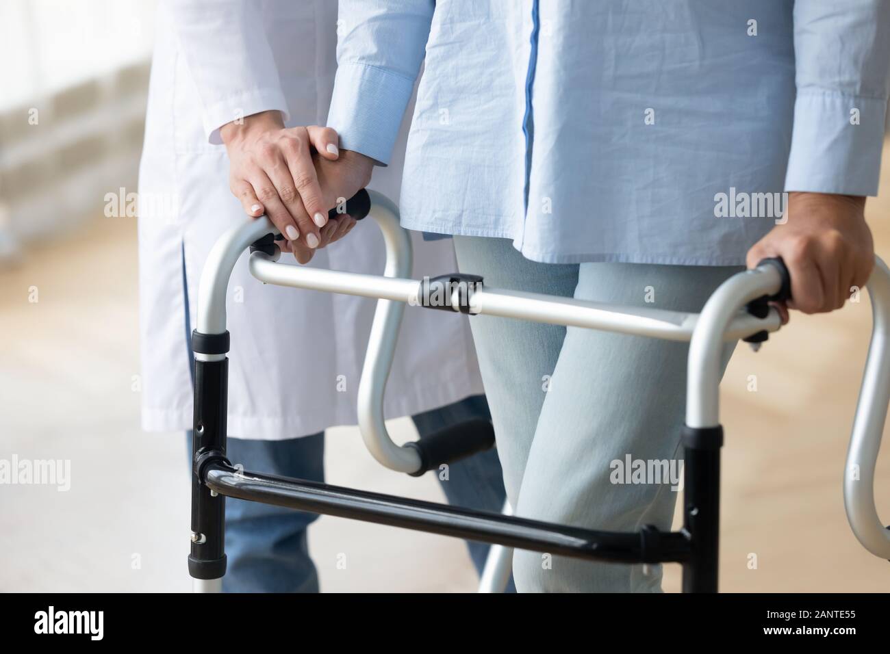 Close up nurse holding disabled older woman hand on walker Stock Photo