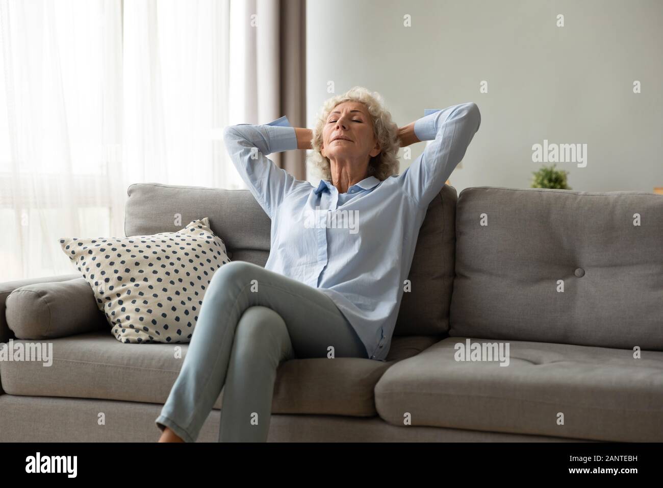 Peaceful older woman sitting on couch, relaxing at home Stock Photo - Alamy