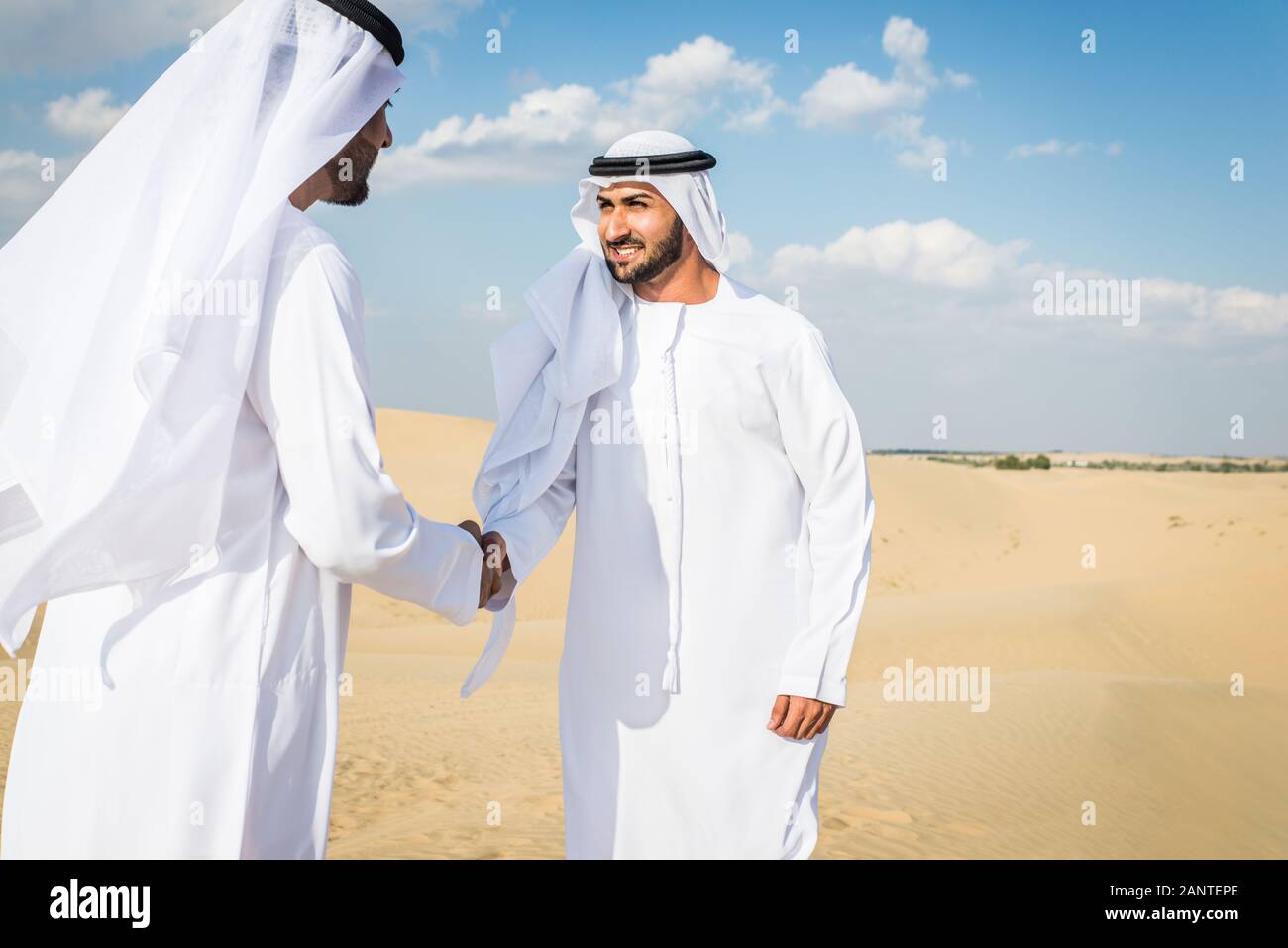 Arabian men witk kandora walking in the desert - Portrait of two middle eastern adults with traditional arabic dress Stock Photo