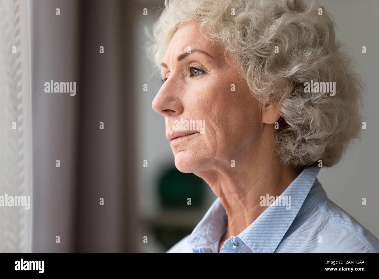 Close up thoughtful older woman looking out window at home Stock Photo