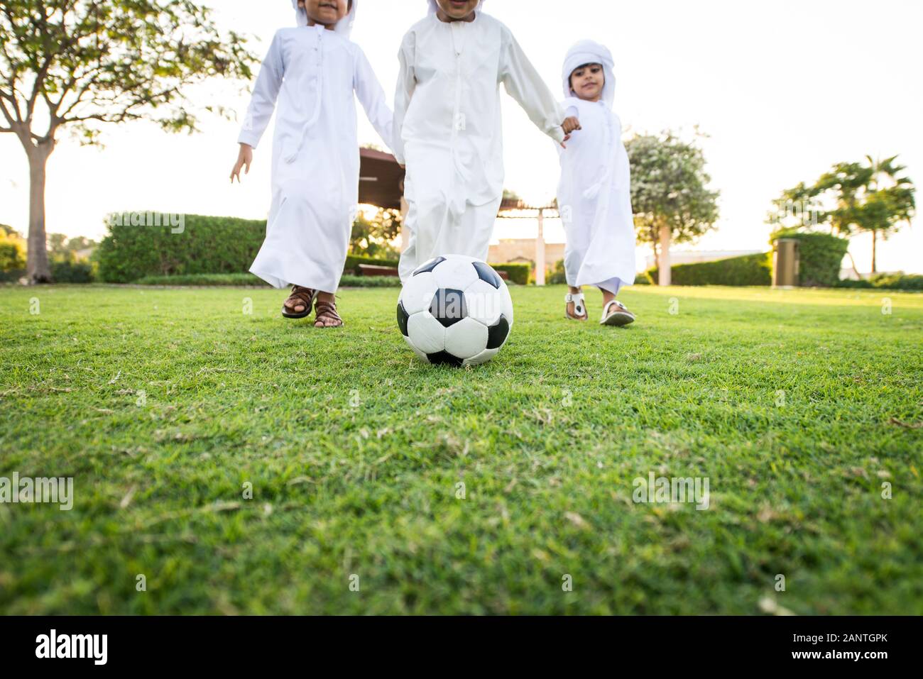 Group of middle-eastern kids wearing white kandora playing in a park in Dubai - Happy group of friends having fun outdoors in the UAE Stock Photo