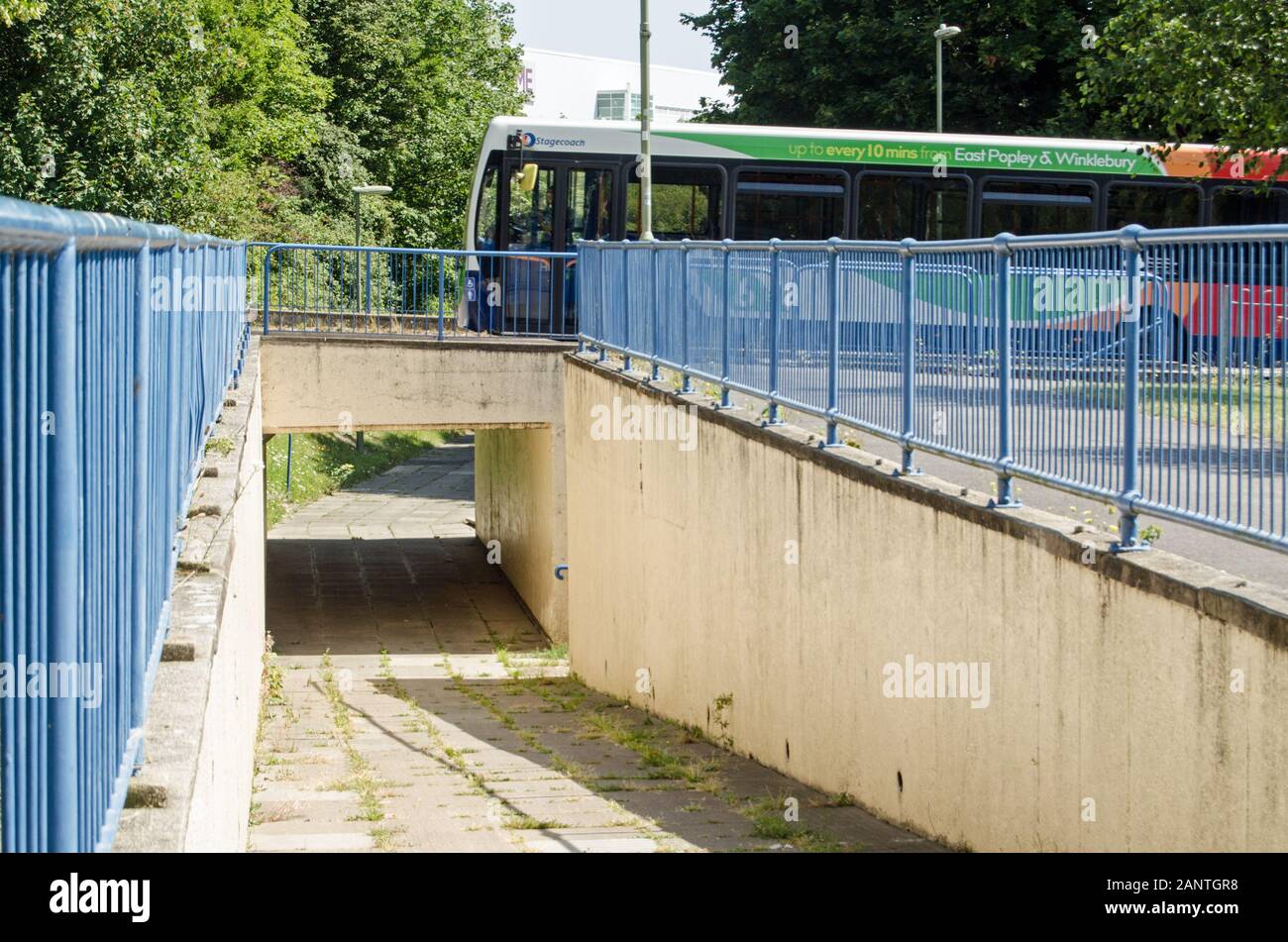 Basingstoke, UK - July 23, 2019:  Pedestrian footpath passing underneath a main road with a bus travelling overhead.  Sunny summer day in the Winklebu Stock Photo