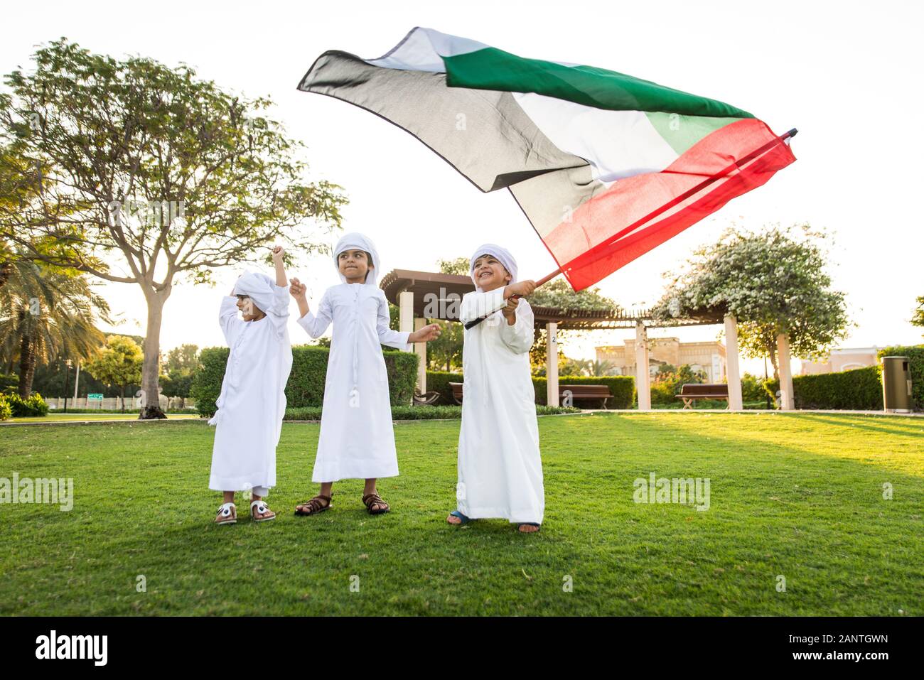 Group of middle-eastern kids wearing white kandora playing in a park in Dubai - Happy group of friends having fun outdoors in the UAE Stock Photo