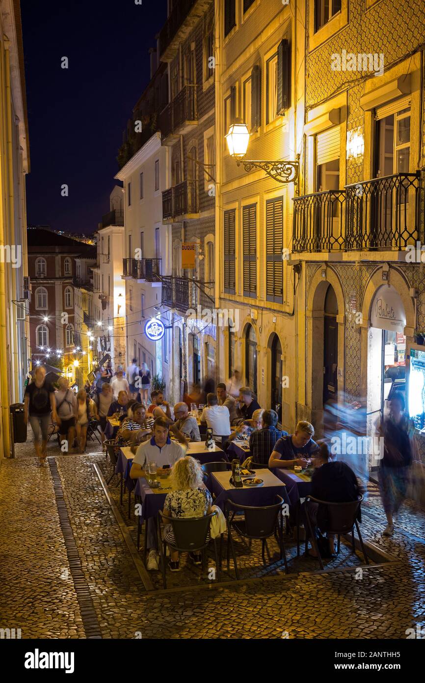 People dining al fresco at Calcada do Duque, cobblestoned pedestrian street that connects Bairro Alto and Rossio in Lisbon, Portugal, in the evening. Stock Photo