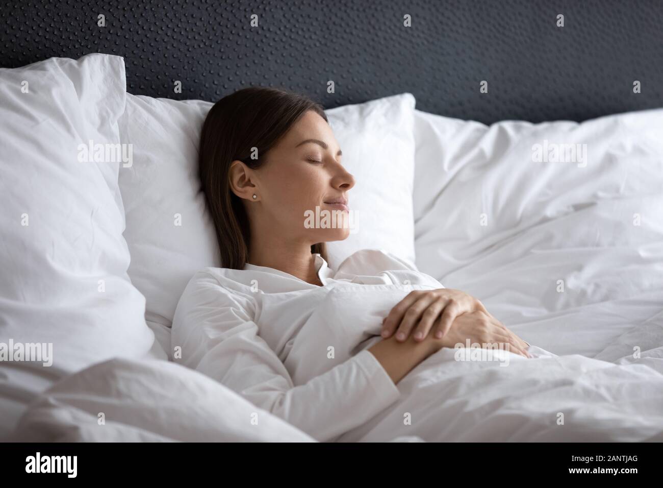 Serene beautiful woman sleeping under warm blanket in comfortable bed Stock Photo Alamy