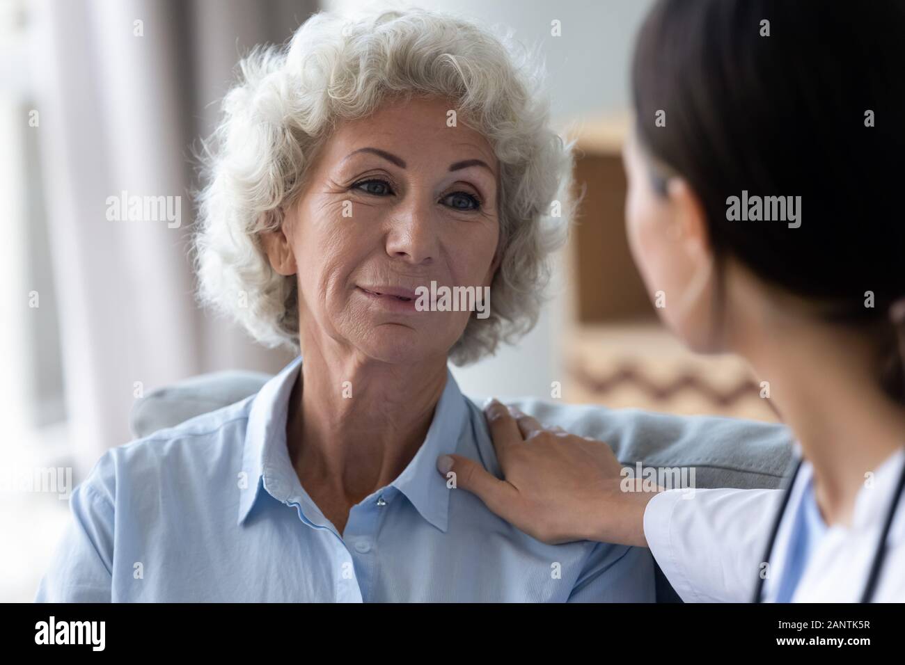 Head shot caring nurse supporting beautiful older woman, touching shoulder Stock Photo