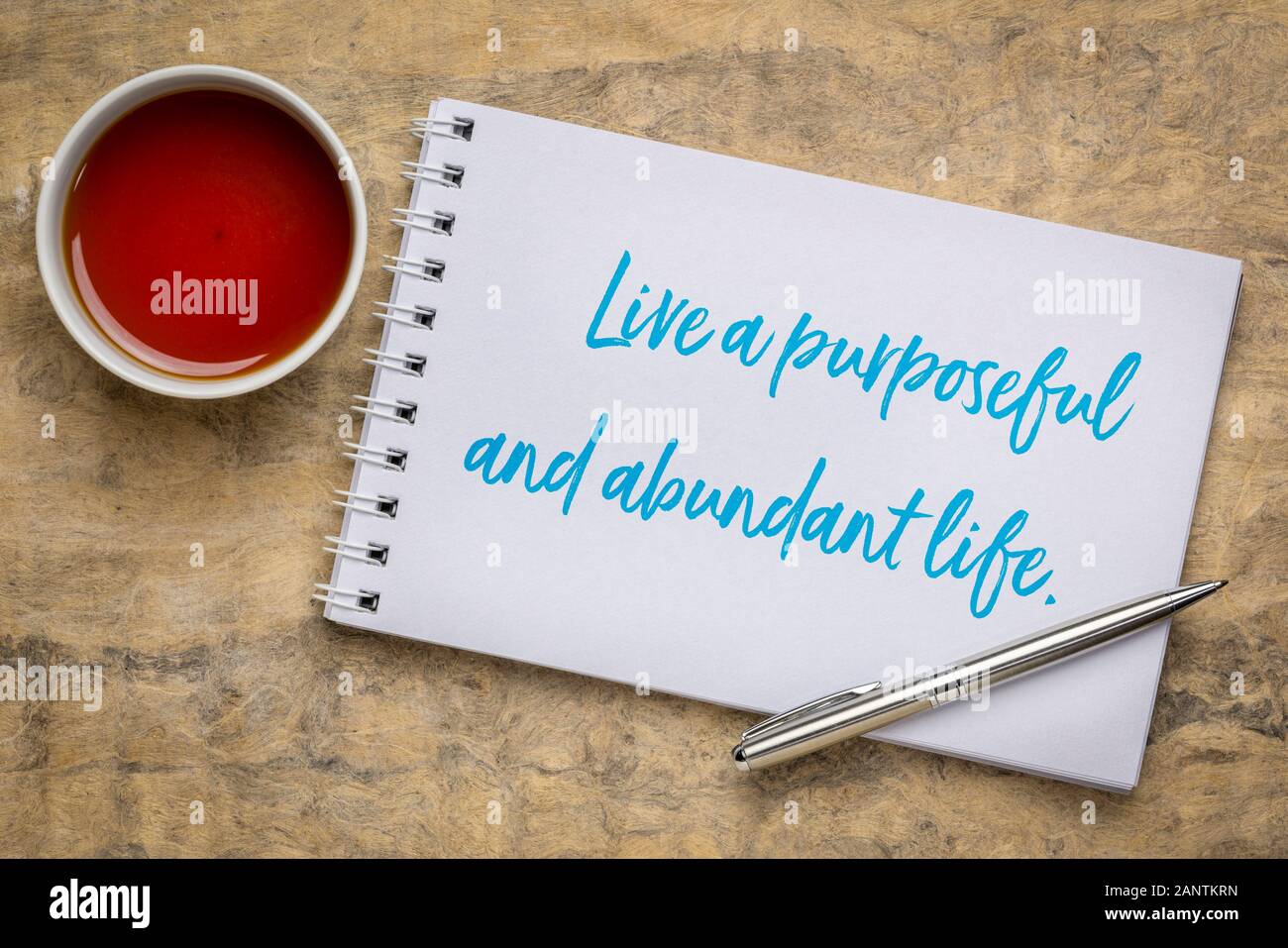 live a purposeful and abundant life - inspirational handwriting in a sketchbook with a cup of tea, success, happiness and personal development concept Stock Photo