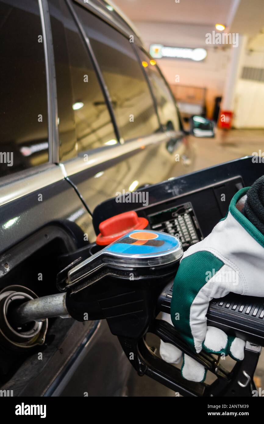 Fueling up a car with diesel at a service station with gloves on to protect hands Stock Photo