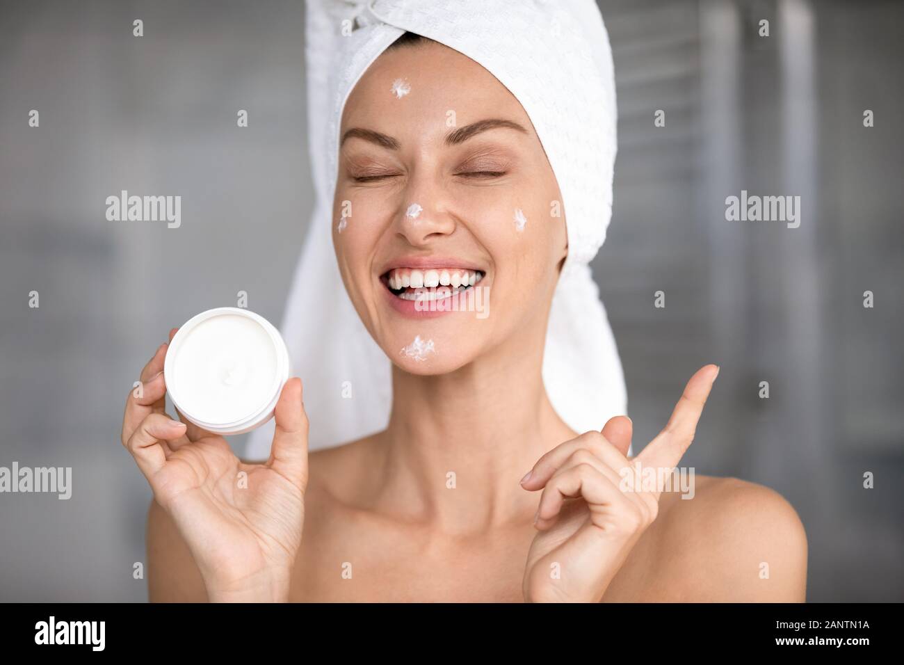 Head shot laughing funny beautiful woman holding face cream Stock Photo