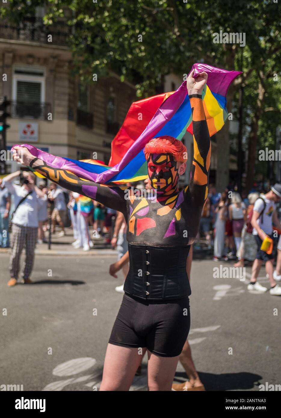 June 29 2019, Paris, France. Gay Pride Parade Day. Young man holding a flag. His face and body are painted ! Beautiful design & motives. Stock Photo