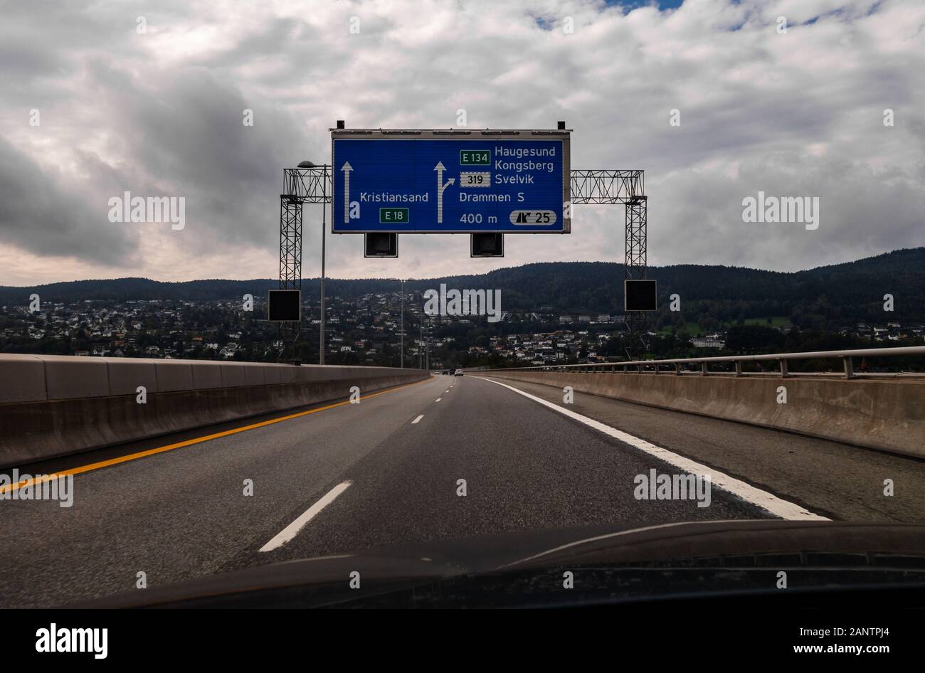 Drammen Norway View from the highway of the city that with the buildings alongside the ridge with a sign above the road Stock Photo