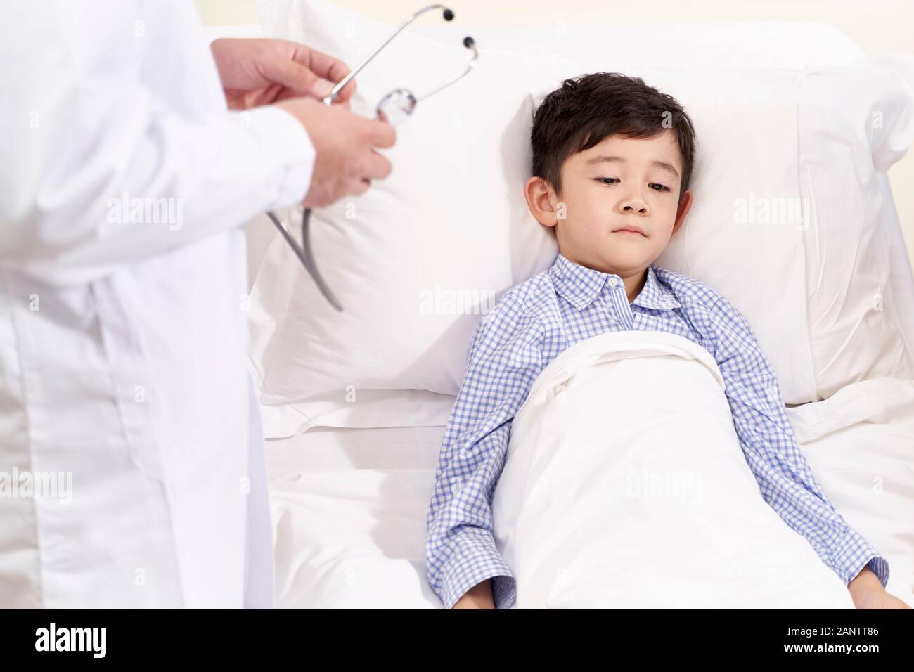 five year old child lying in bed in hospital ward looking sad and depressed Stock Photo