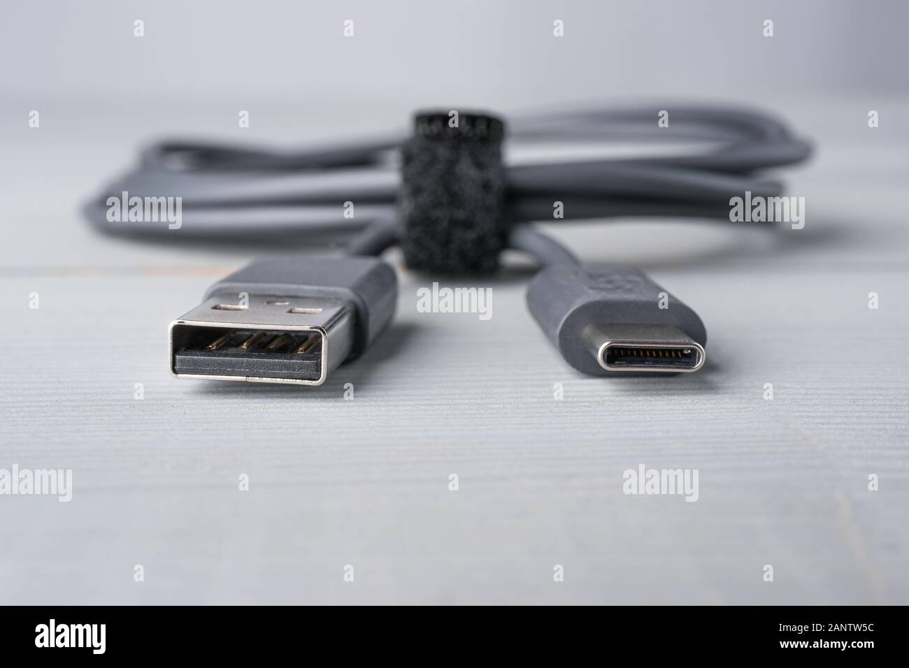 USB Type C and A connector with a grey cable on a wooden background. Closeup with shallow depth of field. Copy space on the bottom. Stock Photo