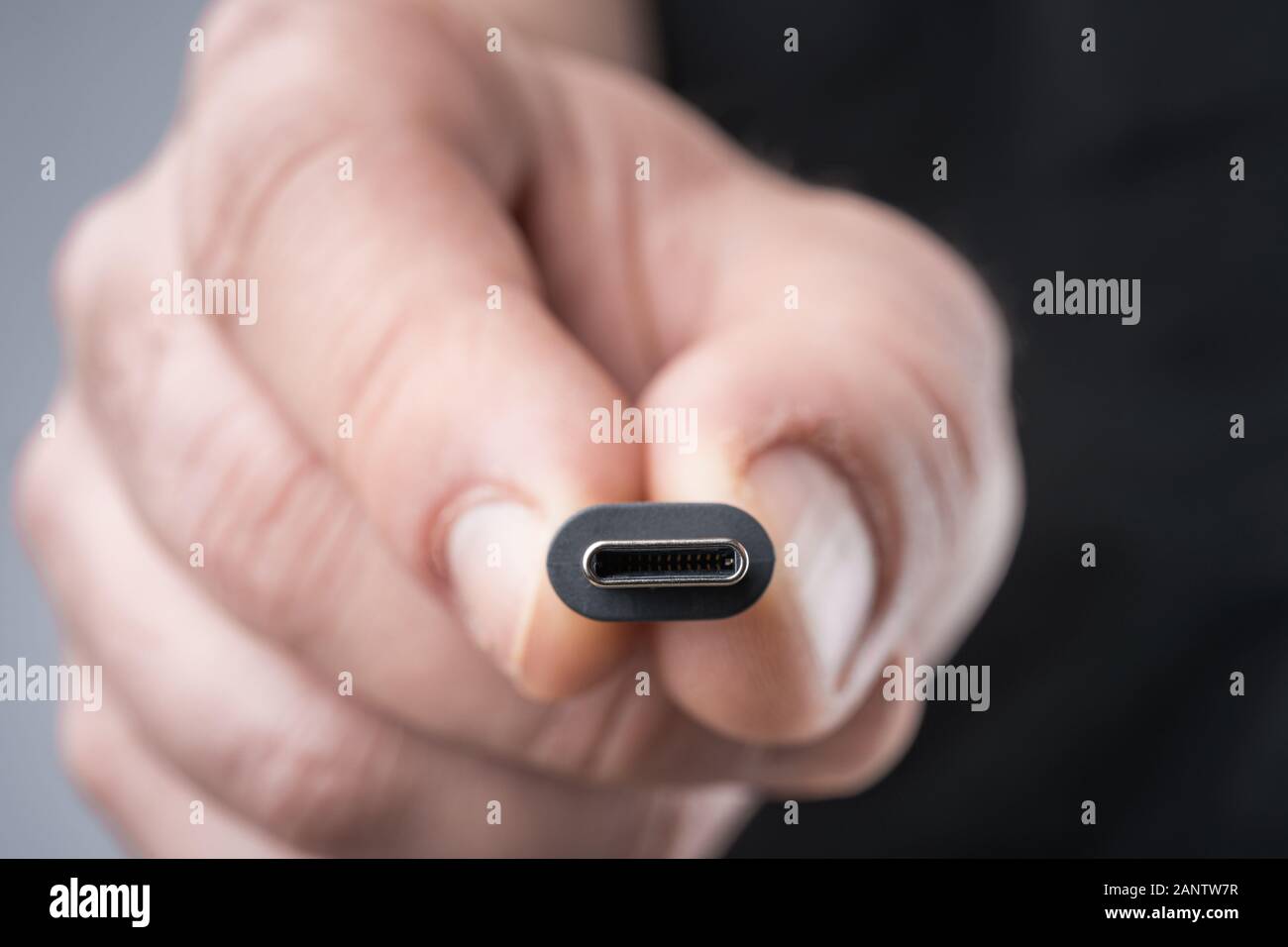 USB Type C connector with a grey cable being held in hand. Shallow depth of field. Stock Photo
