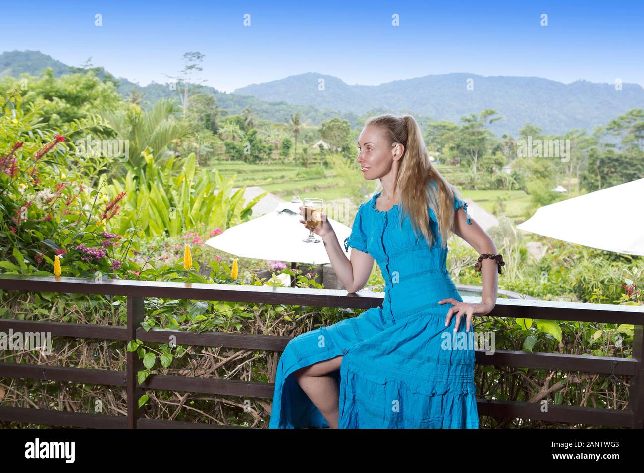 beautiful woman with long blond hair in a long blue dress with a glass ...